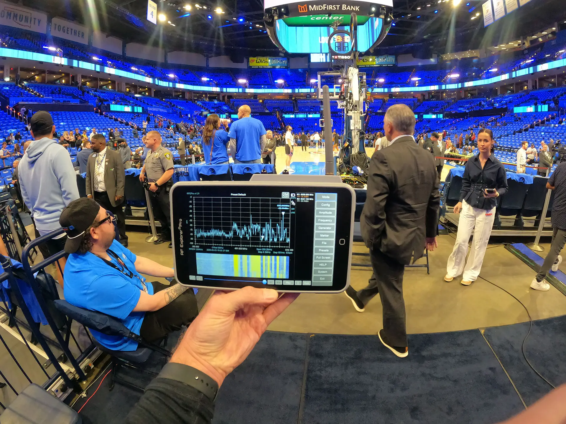 CNS technician monitoring RF frequencies courtside during an Oklahoma City Thunder game to support broadcast integration and wireless coordination inside the arena.